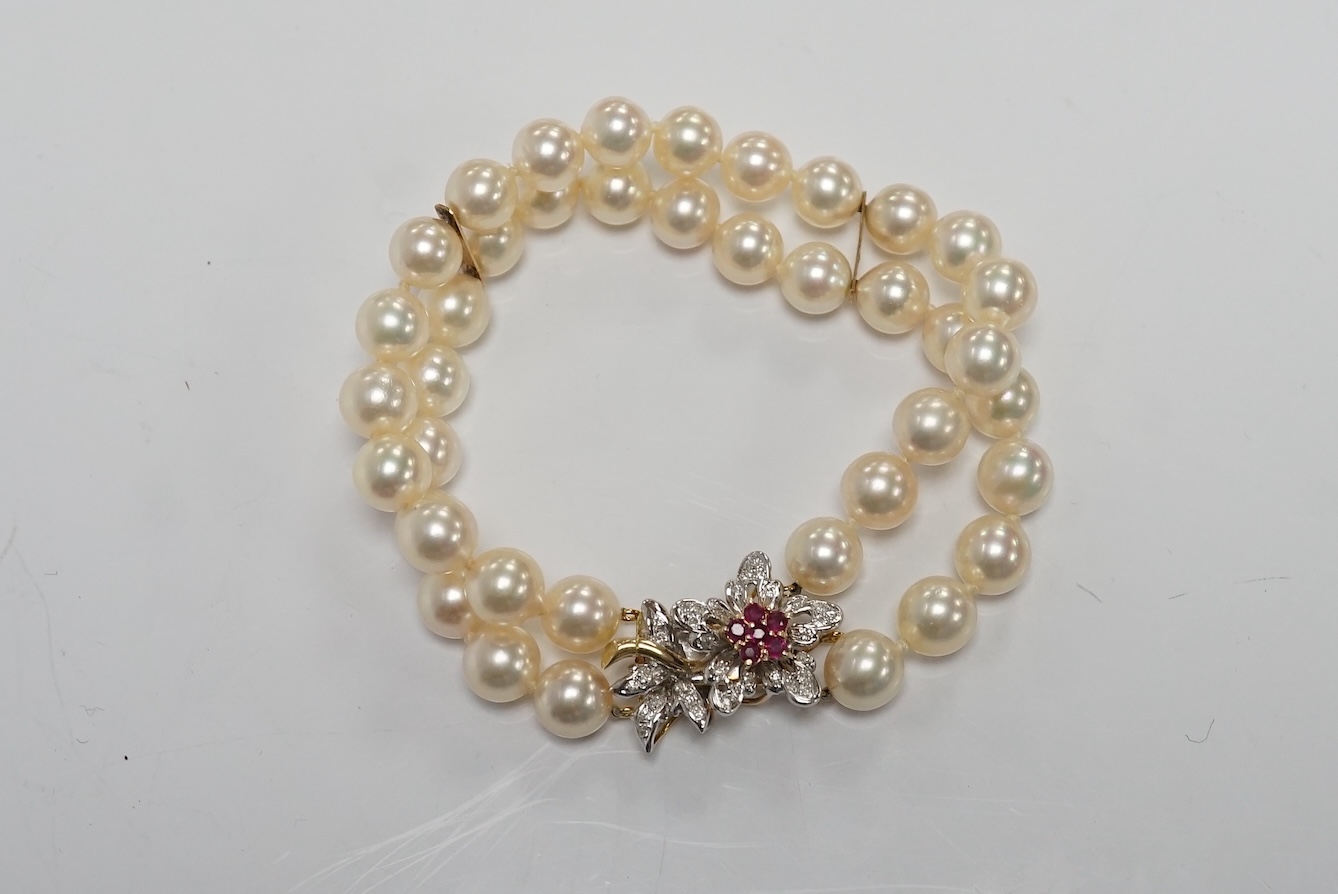 A double strand cultured pearl bracelet, with a ruby and diamond cluster set 14k clasp, 17.3cm. Condition - good